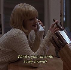 a woman sitting at a table talking on a cell phone with the caption what's your favorite scary movie?