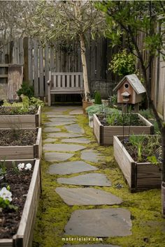 A garden path with stone steps, surrounded by raised beds and a wooden bench.