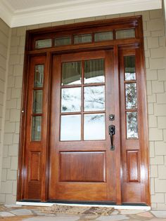 a dog is sitting in front of a wooden door with glass panes on it