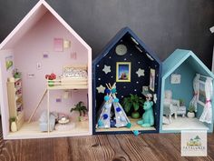 three small doll houses sitting on top of a wooden table