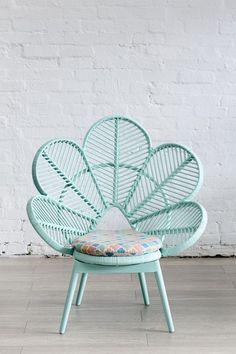 a green chair with a flower shaped seat cushion on it's back in front of a white brick wall