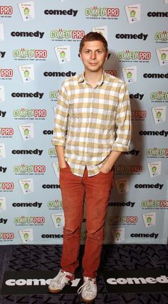 a young man standing in front of a blue and white wall with the words comedy on it