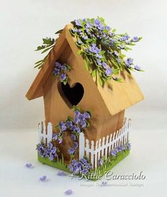 a bird house with purple flowers on the roof