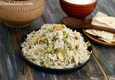 a bowl filled with rice and peas next to tortilla chips on a wooden table