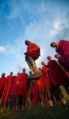 a group of men dressed in red standing next to each other on top of grass