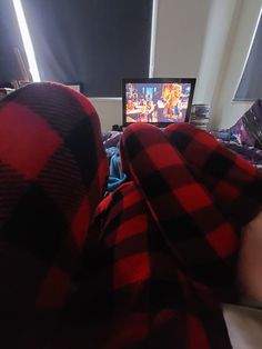 a person in a red and black blanket watching tv