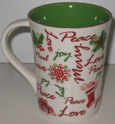 a green and white coffee mug with words written on the side, christmas decorations around it