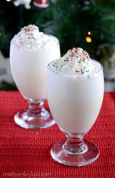 two glasses filled with whipped cream and sprinkles on top of a table