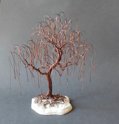 a wire tree is sitting on top of a white rock and looks like it's growing out of the ground