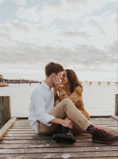 a man and woman sitting on a dock kissing