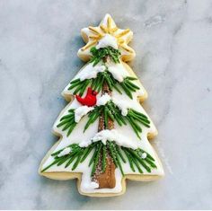 a decorated christmas tree cookie sitting on top of a marble countertop next to a red bird