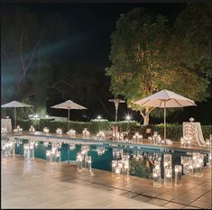 an outdoor pool with candles and umbrellas next to it