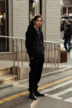 a young man is standing on the street listening to music