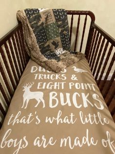 a baby crib with a brown and white comforter on it's side