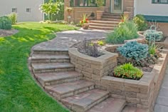 a brick patio with steps leading up to the front door and landscaping area in the foreground