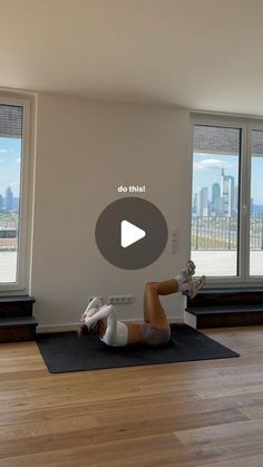 a person is doing yoga on a mat in front of large windows with city view