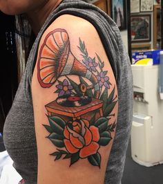 a woman with a tattoo on her arm has an old record and flowers around it