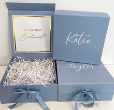 two blue boxes with white and gold confetti in them, one has a card that says will you be my bride?