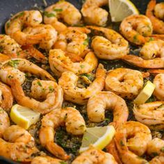 cooked shrimp in a skillet with lemon wedges and parsley