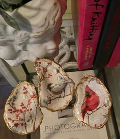 three birds sitting on top of two oysters in front of a bookshelf