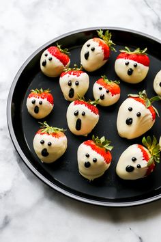 chocolate covered strawberries are arranged in the shape of panda faces on a black plate