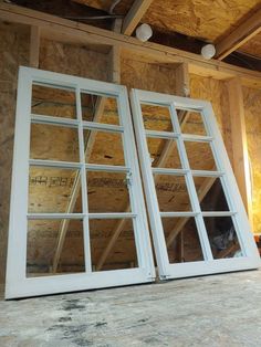 an unfinished room with two windows and some insulation on the walls, in front of a wall that has been built into it