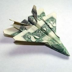 a dollar bill origami fighter jet made out of one hundred dollars, on a white background