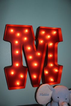 the letter m is lit up with red lights and an elephant toy next to it