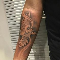 a man's arm with a bird tattoo on the left side of his arm