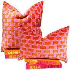 two orange and pink pillows sitting next to each other on top of three bookends