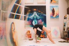 a woman is doing yoga in front of paintings