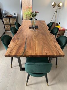 a large wooden table with green chairs around it and a vase on top of the table