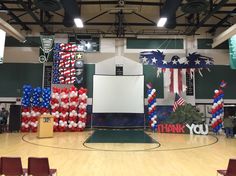 an indoor basketball court decorated with american flags and balloons