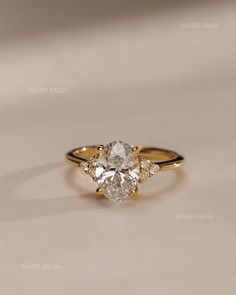 an oval diamond ring with three smaller diamonds on the band, set in yellow gold