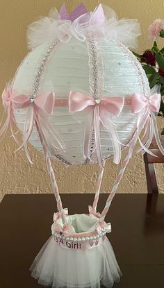 a white basket with pink bows on it sitting on top of a table next to a vase