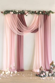 a wedding ceremony with pink drapes and flowers on the floor, along with candles