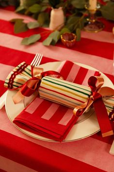 a red and white striped table cloth with bows on it is set for a festive dinner