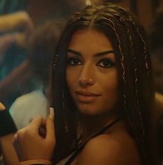 a woman with dreadlocks standing in front of a group of other people at a party