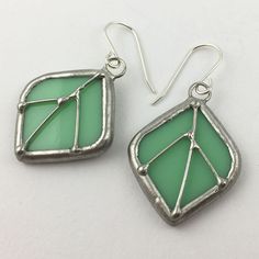 "Opaque, light mint green stained glass earring pair edged in silver, accented with silver wire. The simple French hook ear wires are sterling silver.  Total Size: 1 3/4\" x 7/8\" each Each item by Faerie Glass is 100% uniquely hand-crafted with quality materials that are lead-free. NOTE - All photographs are taken in effort to best represent the product. Color of actual jewelry may vary slightly from photographs." Stained Glass Jewelry Earrings, Nickel-free Recycled Glass Earrings As Gift, Nickel-free Silver Earrings With Recycled Glass, Modern Green Glass Earrings, Nickel-free Green Leaf-shaped Jewelry, Green Leaf-shaped Sterling Silver Earrings, Stained Glass Earrings, Marble Necklace, Nickel-free Green Glass Earrings