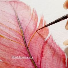 someone is painting a pink feather with watercolors