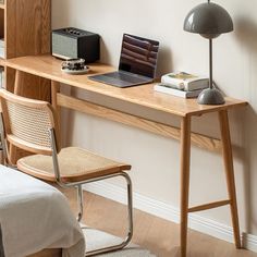 a laptop computer sitting on top of a wooden desk next to a lamp and chair