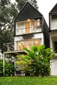 two black and white houses with trees in the back ground, one has a balcony