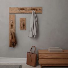 a coat rack and purse hanging on the wall next to a wooden cabinet with pegs