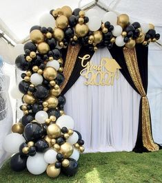 a balloon arch with black, white and gold balloons