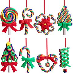 christmas ornaments are hanging from red and green ribbons on white sticks with candy canes