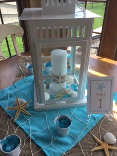 a table set up with candles and seashells for an ocean themed centerpiece