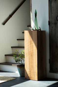 a wooden box sitting on top of a floor next to a plant in a pot