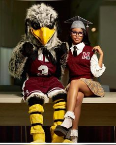 a woman sitting on top of a bench next to an eagle mascot wearing a hat