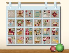 a cross stitch christmas calendar on a wall with ornaments and decorations in front of it