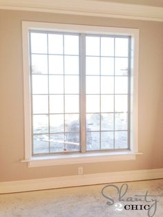 an empty room with a large window and no curtains on the windowsill, in front of a white painted wall